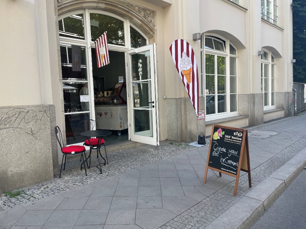 Aussenansicht der Eis-Zauberei Berlin-Mitte mit bunten Beachflags und Eisfahne