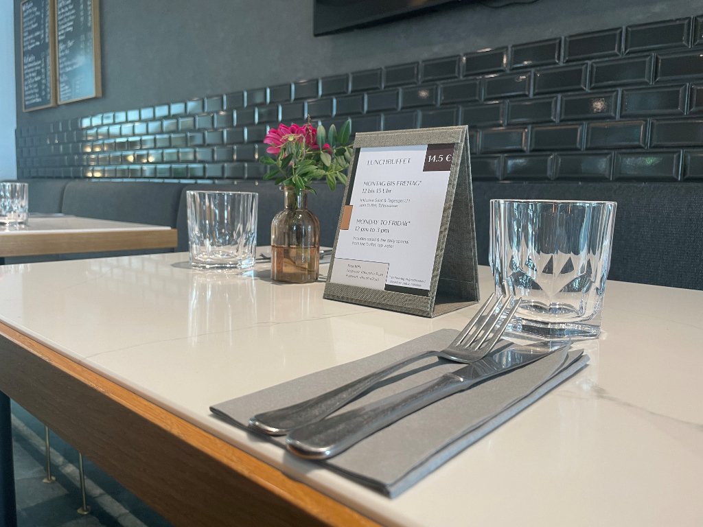 Tisch mit kleinem Aufsteller , Besteck, Wasserglas und keine Vase mit Blumen