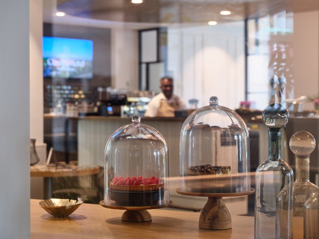 Kuchenständer im Hintergrund die Bar der UNA Tagesbar