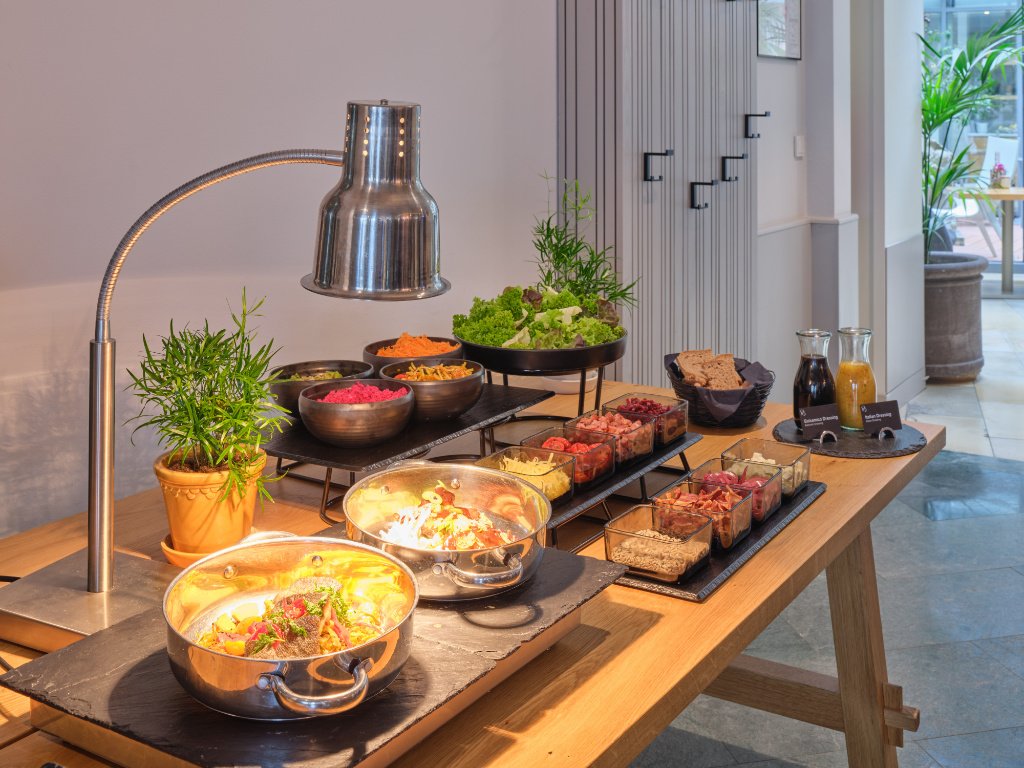 xr:d:DAF76zxlpP8:125,j:5488054086008392595,t:24020713 Buffet mit warmen Speisen und Salaten zur Mittags-Jause in der UNA Tagesbar Berlin